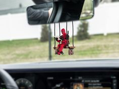 a deadpool doll hanging from the side of a car's dash board in front of a mirror