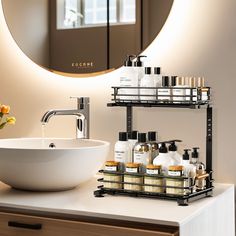 a bathroom sink sitting under a mirror next to a white bowl filled with soap and lotion