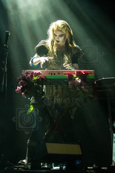 a woman standing in front of a keyboard on stage