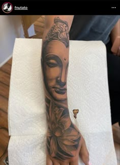 a person's arm with a buddha tattoo on it and a flower in the middle