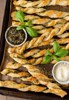 breadsticks with pesto and parmesan cheese on a baking sheet next to dipping sauce