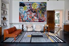 a living room filled with furniture and a large painting hanging on the wall above it