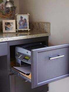 an open drawer in a bathroom next to a counter with pictures on the wall behind it