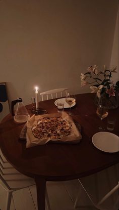 a wooden table topped with a pizza on top of a pan next to a candle