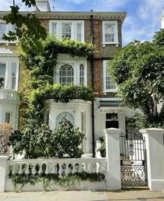 a large white house with ivy growing on it's walls and gated entrance