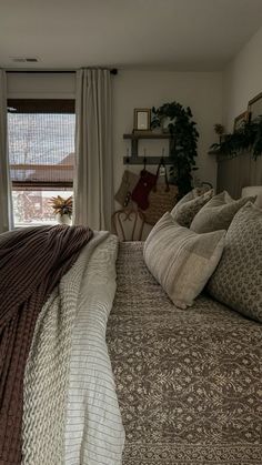 a large bed sitting next to a window in a room with curtains on the windowsill