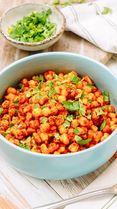 a blue bowl filled with chickpeas and garnished with green leaves on top