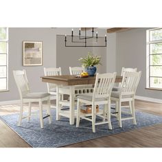 a dining room table with white chairs and a blue rug in front of the table