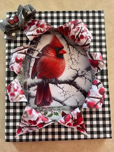 a red bird sitting on top of a black and white checkered table cloth