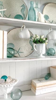 a shelf filled with plates and vases on top of white shelves next to books