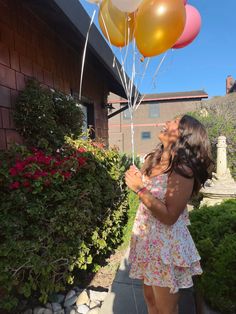 a woman holding several balloons in her hand