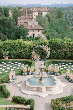 an aerial view of a formal outdoor wedding ceremony in the garden with seating and fountain