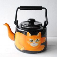 a black tea kettle with an orange cat painted on it's front and side