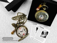 an open pocket watch sitting on top of a table next to some cards and a pen