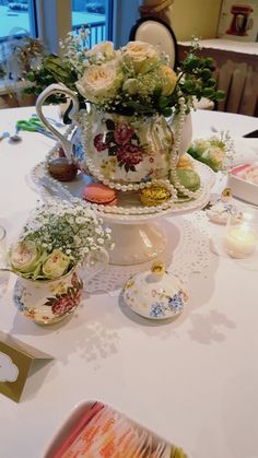 there is a tea pot with flowers in it on top of a table next to other dishes