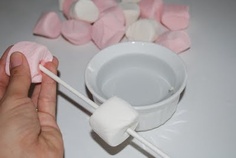 marshmallows in a white bowl being dipped with pink and white sugar