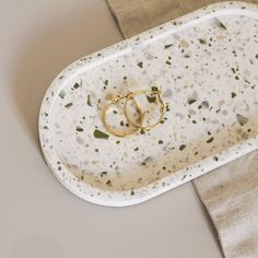 two gold wedding rings are placed on a white platter that is sitting on a linen napkin