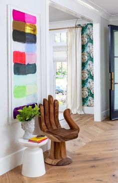 a chair sitting on top of a hard wood floor next to a wall mounted painting