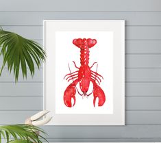 a red lobster art print hanging on a wall next to a potted palm tree