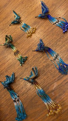 several pieces of beaded art on a wooden table with beads in the shape of birds