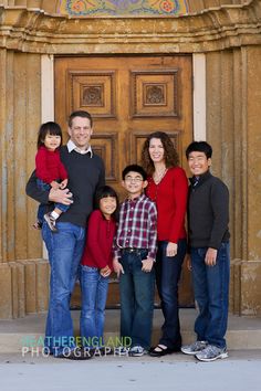 a family poses in front of an ornate door