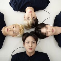 four people are standing in a circle with their heads turned to the same direction and one person is wearing headphones