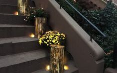 some yellow flowers are sitting on the steps next to each other and lit by lights