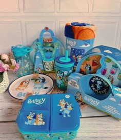 there are many children's toys on the table and one has a blue lunch box