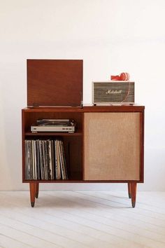 an old record player sitting on top of a wooden cabinet with vinyl records in it