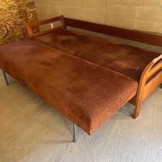 a brown couch sitting on top of a white floor next to a wooden bench with metal legs