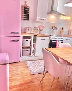 a pink refrigerator in a kitchen next to a table