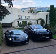 two black sports cars parked next to each other in front of a large white building