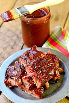 barbecue ribs with bbq sauce on a plate next to a jar of ketchup