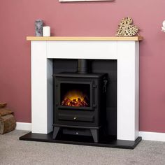 a fireplace with a fire burning in it next to a brown chair and pink wall