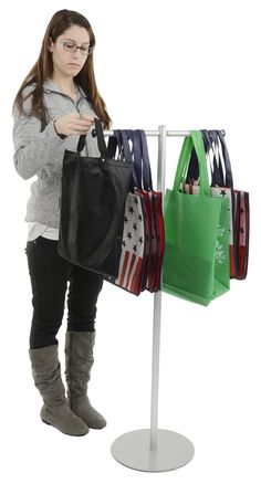 a woman standing next to a rack with bags on it and another bag in front of her