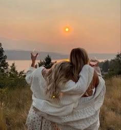 two women hug each other as the sun sets