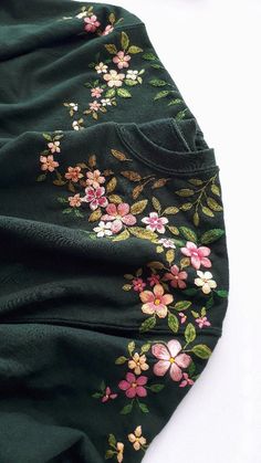 a green dress with pink flowers on it and gold trimming around the neckline