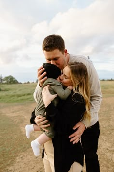 a man and woman holding a baby in their arms