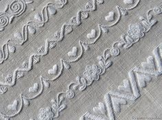 white lace with hearts and swirls is shown on a piece of fabric that has been stitched together