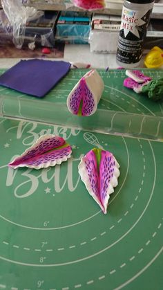 some paper flowers sitting on top of a green table with white circles and lines around them