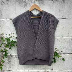 a sweater hanging up against a white brick wall