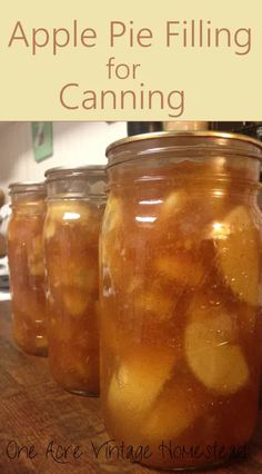 four jars filled with apple fillings on top of a wooden table next to an oven