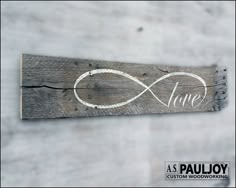 a wooden sign with the word love and an infinite symbol painted on it's side