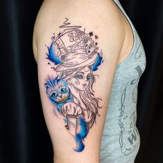 a woman's arm with a cat and hat tattoo on her left upper arm