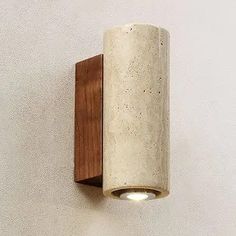 a wall light mounted on the side of a white wall with a wood frame and wooden trim