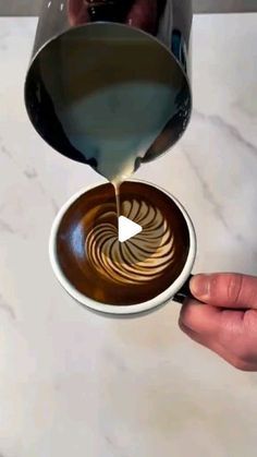 someone pouring coffee into a cup on top of a marble table with white and brown designs