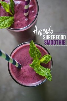 two glasses filled with smoothie next to each other on top of a gray table