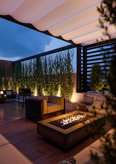 an outdoor living area with couches, tables and fire pit in the evening time