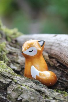 a small toy fox sitting on top of a tree branch