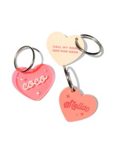 two heart shaped key chains with the word coco on them, one is pink and one is red